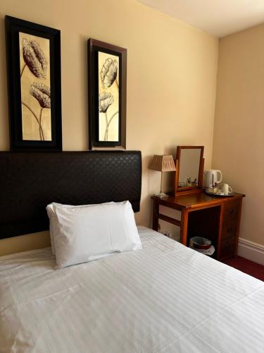 a bedroom with a white bed with two pictures on the wall at The Old Manor House Hotel in Keynsham
