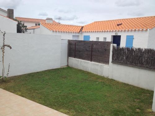 a yard in the backyard of a house with a fence at Maisonnette de vacances Noirmoutier quartier Epine in LʼÉpine
