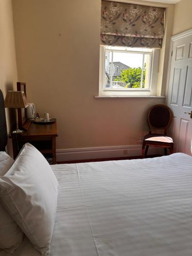 a bedroom with a white bed and a window at The Old Manor House Hotel in Keynsham