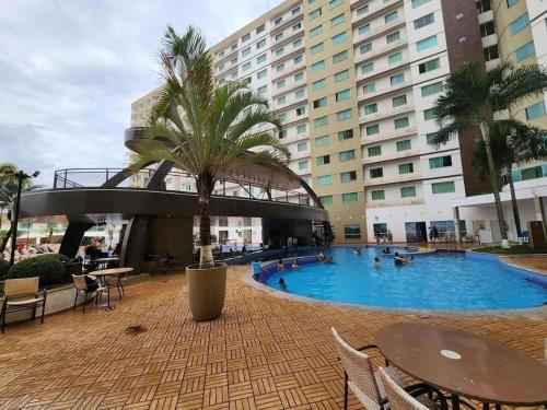 a large swimming pool with a palm tree in front of a building at Apartamentos Riviera Park in Caldas Novas