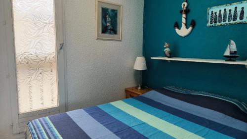 une chambre avec un lit et un mur bleu dans l'établissement St Cyprien la marina T2 climatise, à Saint Cyprien Plage