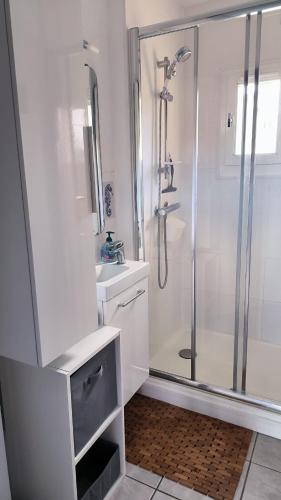 une salle de bain blanche avec une douche et un lavabo dans l'établissement St Cyprien la marina T2 climatise, à Saint Cyprien Plage