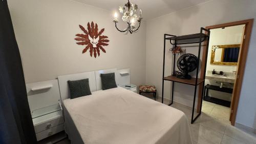 a bedroom with a bed and a mirror and a chandelier at Apartamentos Recanto do Bosque in Caldas Novas