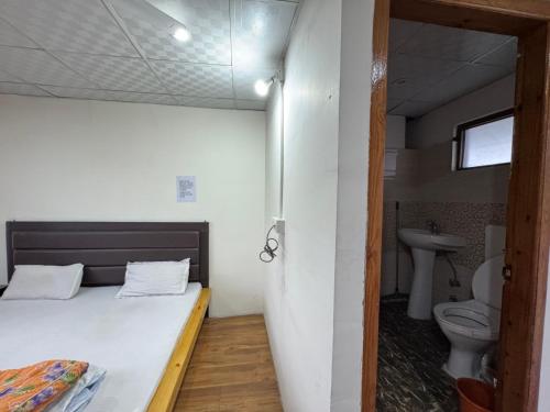 a bedroom with a bed and a sink and a toilet at Highway Inn Guest House in Leh
