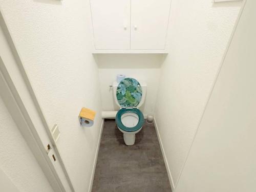 Elle comprend une petite salle de bains pourvue de toilettes avec un siège bleu. dans l'établissement T2 avec Parking - Piscine et Tennis - à 200 m des Plages - FR-1-316-196, à Six-Fours-les-Plages