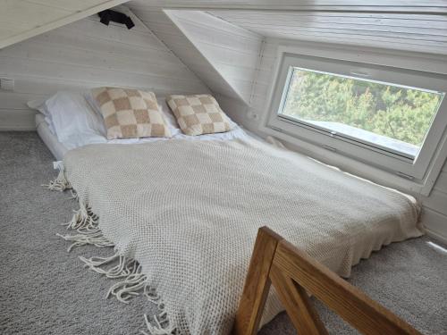 a bed in a small room with a window at Tajnikowo Sekretny Tiny House Anyżek in Łubiana