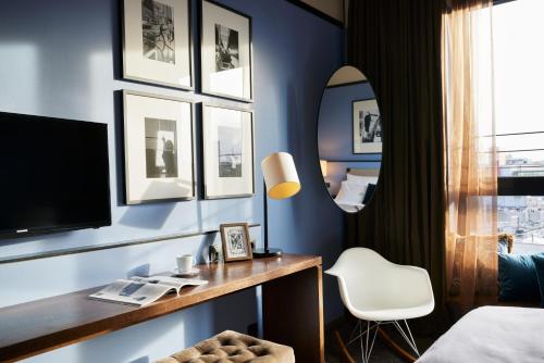 a bedroom with a desk with a tv and a mirror at The George Hamburg in Hamburg