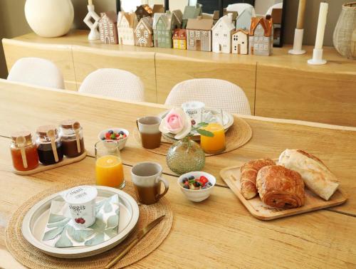 einen Tisch mit einem Frühstück mit Croissants und Orangensaft in der Unterkunft La Maison du Cerisier - Chambre d'hôtes in Senlis
