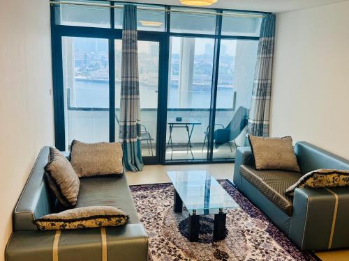 a living room with two couches and a glass table at Wow Amazing BurjKhalifa,Sea,Sunset,Ship,Park,Metro View,Private Home 2BHK ,Fully Furnished in Dubai