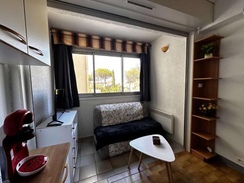 Cette petite chambre comprend un canapé et une fenêtre. dans l'établissement NP200-89-11 2 pièces, Narbonne Plage, à Narbonne-Plage