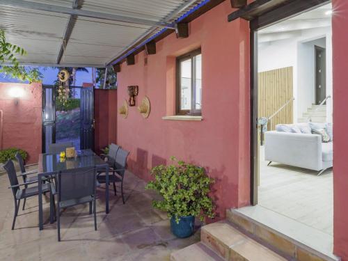 patio ze stołem, krzesłami i czerwoną ścianą w obiekcie Cubo's Finca Las Palmeras w mieście Alhaurín el Grande