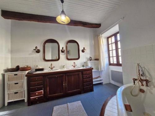une salle de bain avec deux lavabos et une baignoire et deux miroirs dans l'établissement La Maison du Lac, à Estipouy
