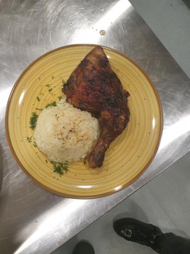 a yellow plate with a piece of meat and rice at Pensiunea Petra Verde in Porumbacu de Sus