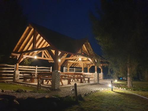 a wooden pavilion with picnic tables at night at Pensiunea Petra Verde in Porumbacu de Sus