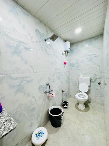 a bathroom with a toilet and a wall covered in marble at Nature View Villa - The Dream Stays ll Big Infinity Pool ll Wifi ll Ac ll Garden in Lonavala