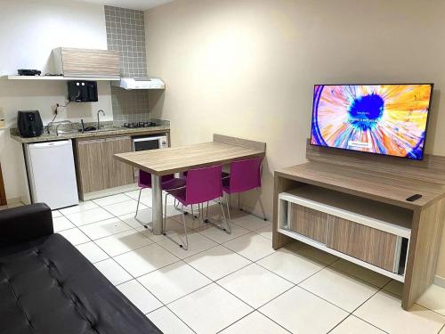 a kitchen with a table and a tv in a room at Apartamentos Riviera Park in Caldas Novas