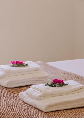three towels with pink flowers on them on a table at Quinta do Pinheiro in Pinheiro