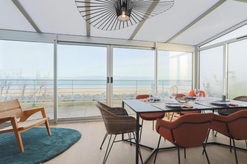 a dining room with a table and chairs and windows at Superbe appartement haut de gamme 4 personnes en Front de mer in Plérin