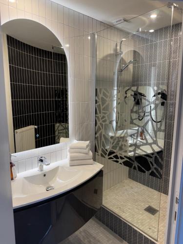une salle de bain avec un lavabo et une douche avec un miroir dans l'établissement Hôtel Restaurant Les Boissières, à Bioule