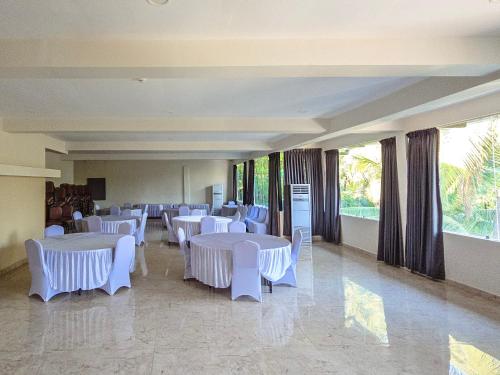 a room with white tables and chairs and windows at The Verda De Miranda Resort Morjim North Goa in Morjim