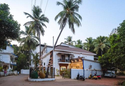 a palm tree towering over a white house at The Verda De Miranda Resort Morjim North Goa in Morjim