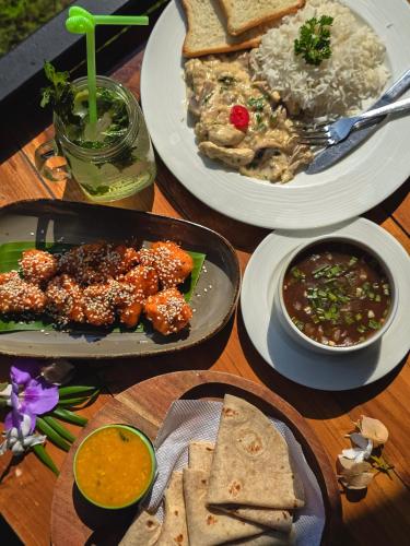 a table topped with plates of food with rice and dips at The Verda De Miranda Resort Morjim North Goa in Morjim