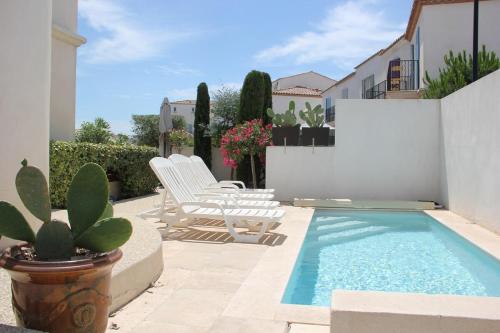 un patio avec des chaises et une piscine dans l'établissement La Batelière, entre mer, Camargue et Canaux, à Aigues-Mortes