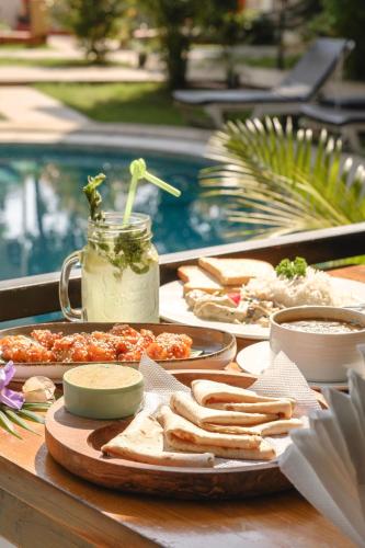 a tray of food on a table next to a pool at The Verda De Miranda Resort Morjim North Goa in Morjim