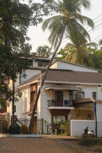 a palm tree leaning over a white house at The Verda De Miranda Resort Morjim North Goa in Morjim