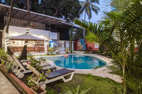a swimming pool with two lounge chairs and an umbrella at The Verda De Miranda Resort Morjim North Goa in Morjim