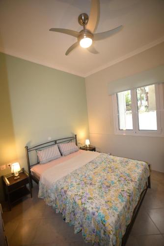 a bedroom with a bed and a ceiling fan at Nicol apartment in Skoutaros