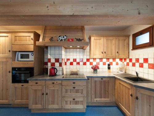 - une cuisine avec des placards en bois et du carrelage rouge et blanc dans l'établissement Appt rénové 3 pièces, 6 couchages, proche centre, ascenseur, lave-vaisselle, lave-linge - FR-1-241-35, au Grand-Bornand