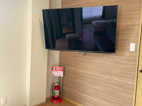 a flat screen tv hanging on a wall with a fire extinguisher at PLEO 圧巻の富士山ビュー バルコニーあり モダンで綺麗な宿を貸し切り Max4名 in Fujiyoshida