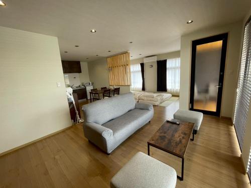 a living room with a couch and a table at PLEO 圧巻の富士山ビュー バルコニーあり モダンで綺麗な宿を貸し切り Max4名 in Fujiyoshida
