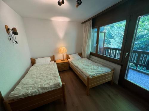two beds in a room with two windows at Mandarin B10 in Crans-Montana