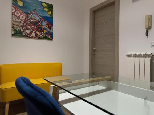 a dining room with a glass table and a yellow chair at Albachiara Apartment vicino al mare di Capaci in Capaci