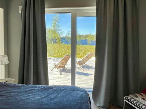 a bedroom with a sliding glass door with chairs outside at Lake Cottage With Sunsets Over Försjön in Eksjö