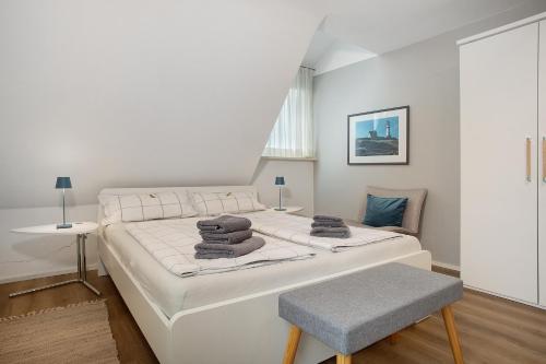 a white bedroom with a large bed and a chair at Gästezimmer Cleo in Uhldingen-Mühlhofen