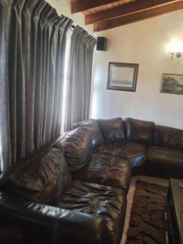 a brown leather couch in a living room with curtains at Halibut Suite in Strand