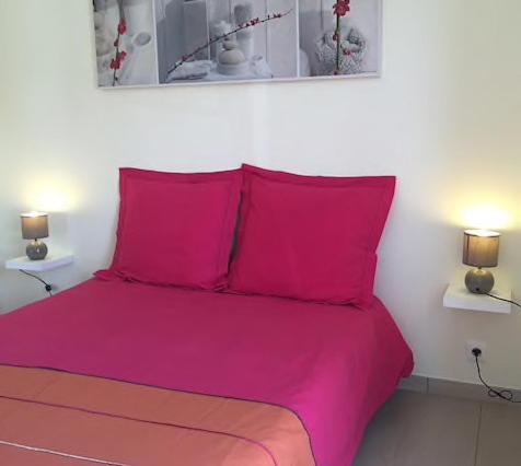 un lit rose avec deux oreillers rouges dans une chambre dans l'établissement Appartement 2slaapkamers, panoramisch zeezicht, à Saint-Raphaël