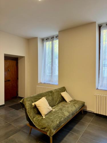 - un canapé vert dans le salon doté de fenêtres dans l'établissement Appartement à Vienne, à Vienne