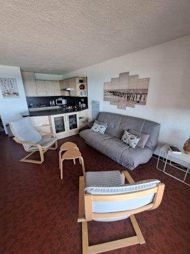 - un salon avec un canapé gris et des chaises dans l'établissement Face à la mer, au Barcarès