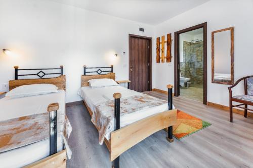 a bedroom with two beds and a chair at Pensiunea Petra Verde in Porumbacu de Sus