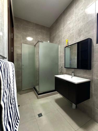 a bathroom with a sink and a shower and a mirror at Luxury House in Brazzaville