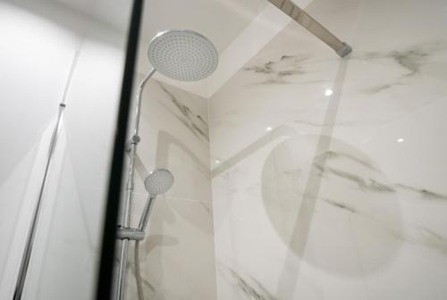 a shower with white marble walls and two shower heads at Tiber Suite in Rome
