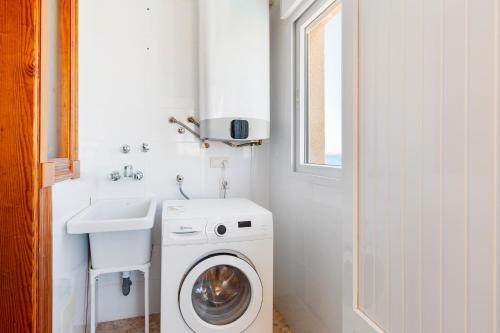 a small bathroom with a washing machine and a sink at Primera linea de playa in La Manga del Mar Menor