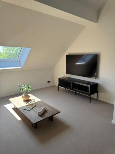 a living room with a flat screen tv and a coffee table at La Barzalière in Chimay