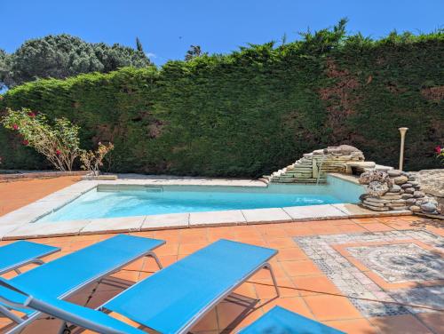 - une piscine avec des chaises longues bleues sur la terrasse dans l'établissement La Plénitude, à Narbonne