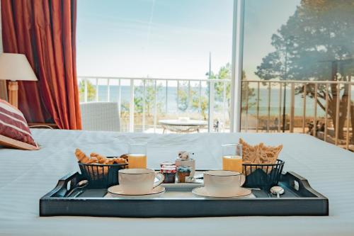 a tray with food and drinks on a bed at Hôtel Édenia - Spa Estime&Sens in Carnac
