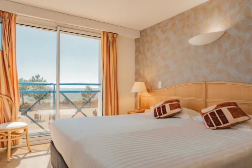a bedroom with a bed and a large window at Hôtel Édenia - Spa Estime&Sens in Carnac